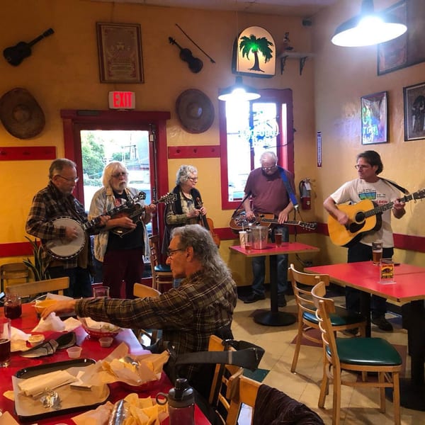 A band plays music in a lively Baja Taqueria dining room with red tables and yellow walls.