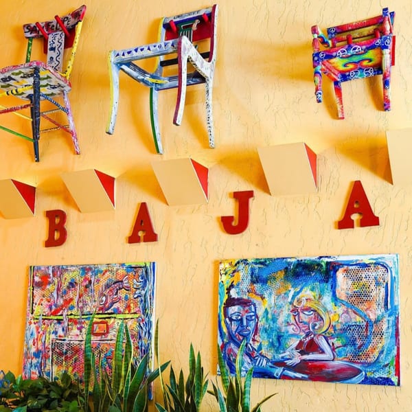 Colorful, eclectic wall decor at Baja Taqueria, featuring painted chairs, "BAJA" letters, and vibrant art.
