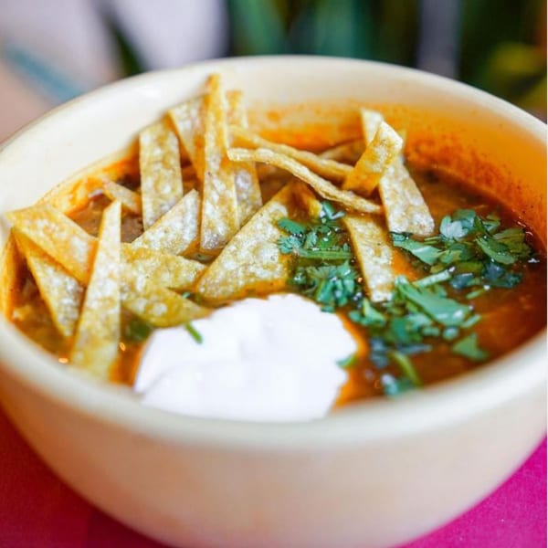 Baja Taqueria's tortilla soup with crispy tortilla strips, sour cream, and cilantro in a bowl.