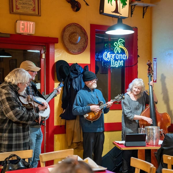 A band plays music in a vibrant Mexican restaurant with a Corona Light neon sign.